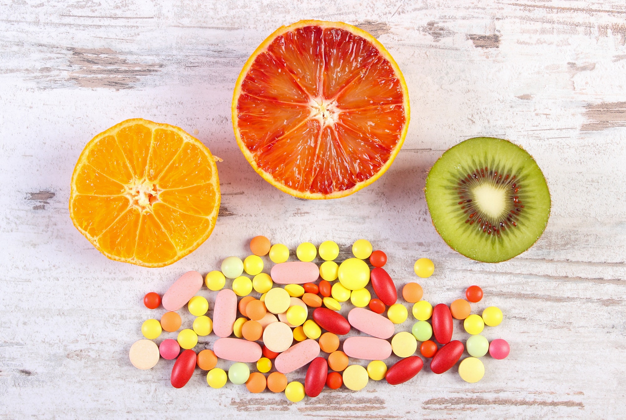 Fresh fruits and colorful medical pills, choice between healthy nutrition and medical supplements